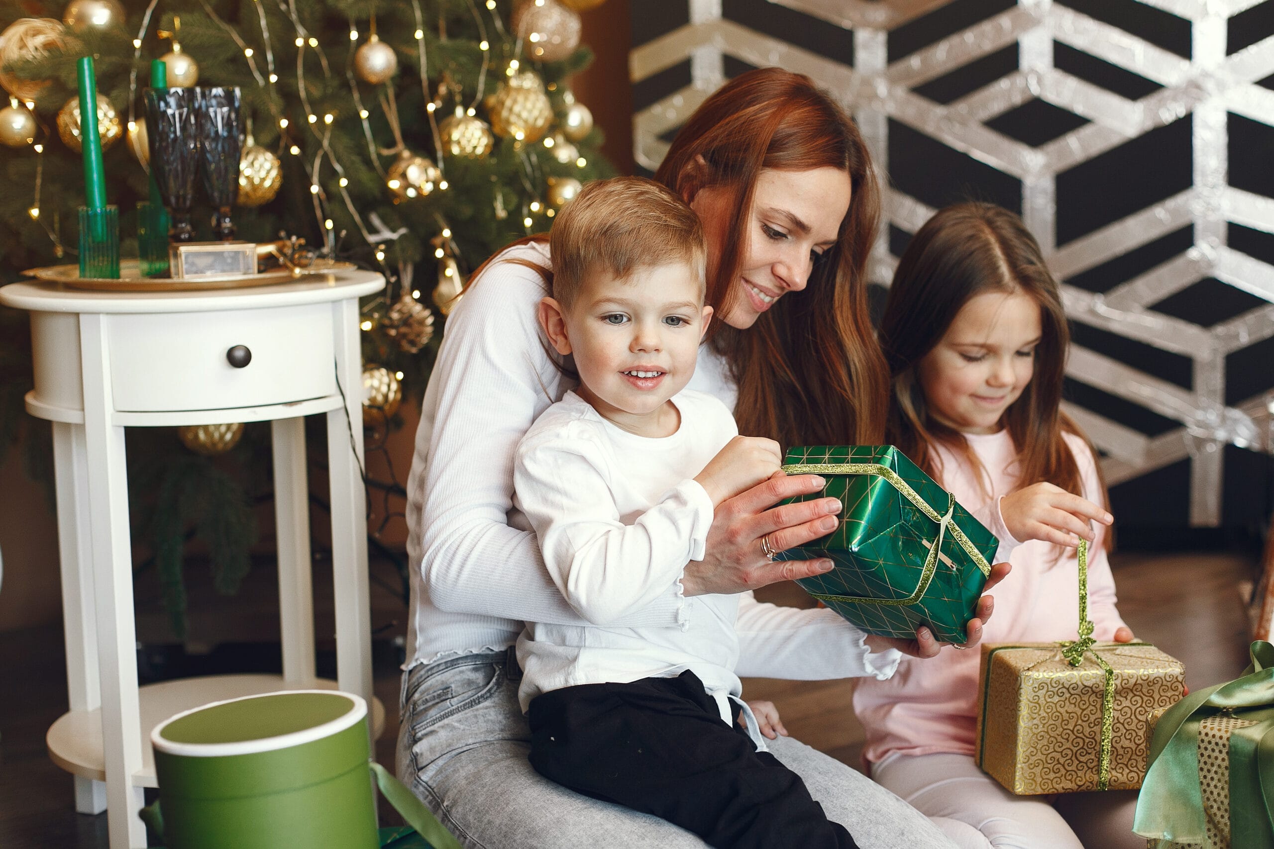 Mother in a white sweater. Family near christmas tree. Little children in a cute sweater